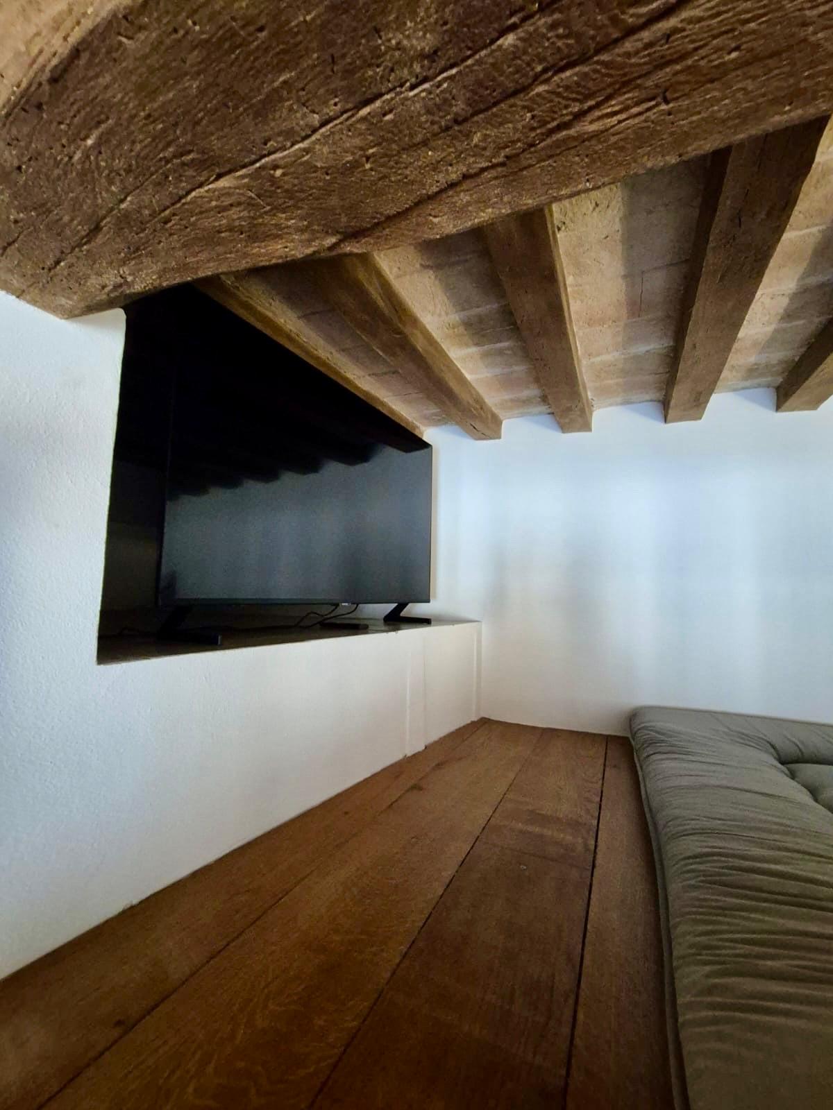 Soppalco con TV e soffitto in travi di legno